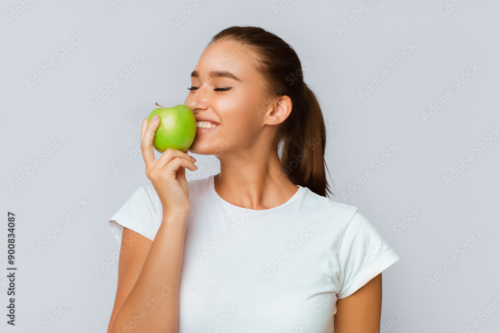 Healthy Nutrition. Cheerful Girl Eating Apple Standing Over White Studio Background. Isolated Healthy Nutrition. Cheerful Girl Eating Apple Standing Over White Studio Background. Isolated