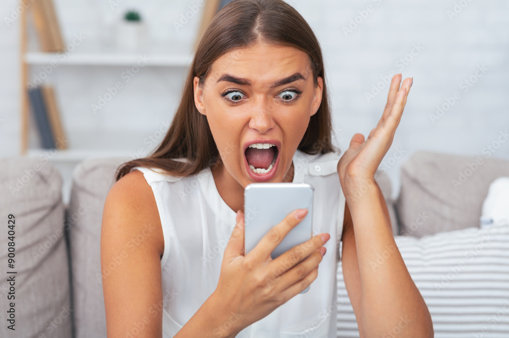 Phone Quarrel. Furious Girl Screaming On Smartphone Sitting On Couch Indoor. Selective Focus Phone Quarrel. Furious Girl Screaming On Smartphone Sitting On Couch Indoor. Selective Focus