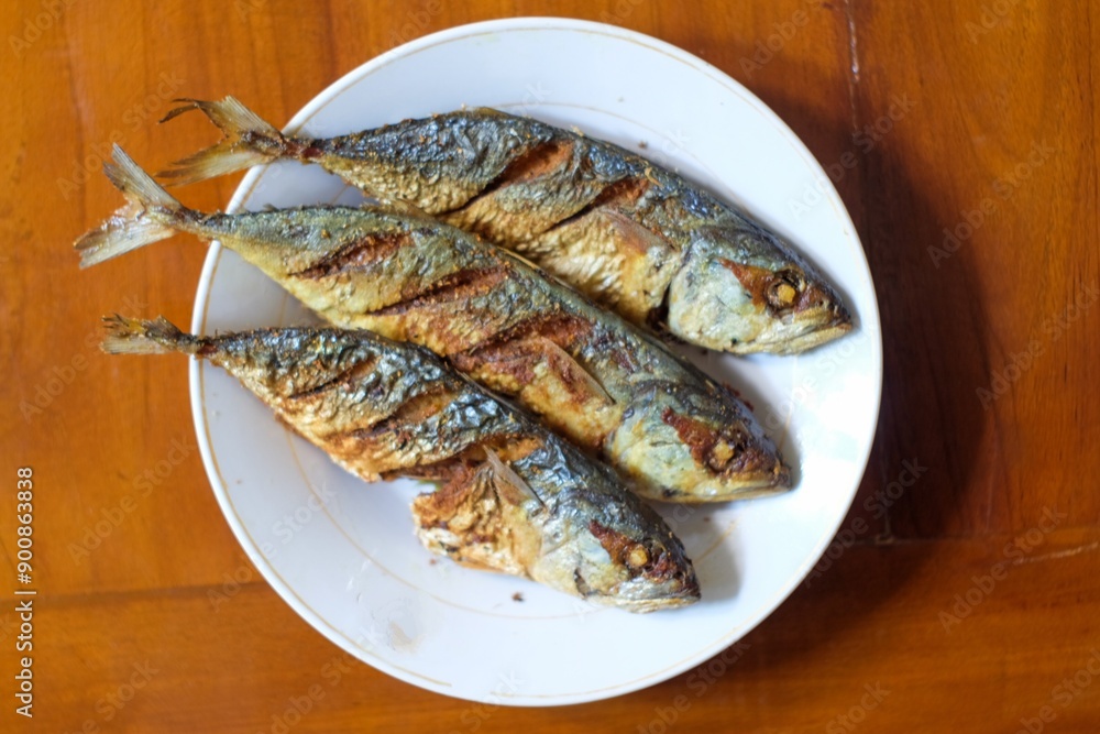 Fried mackerel in a white plate on a wooden table, healthy seafood concept, copy space. Fried mackerel in a white plate on a wooden table, healthy seafood concept, copy space.