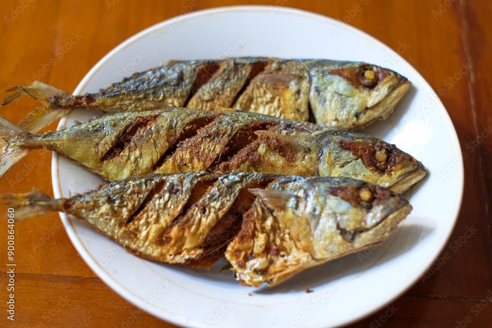 Fried mackerel in a white plate on a wooden table, healthy seafood concept, copy space. Fried mackerel in a white plate on a wooden table, healthy seafood concept, copy space.
