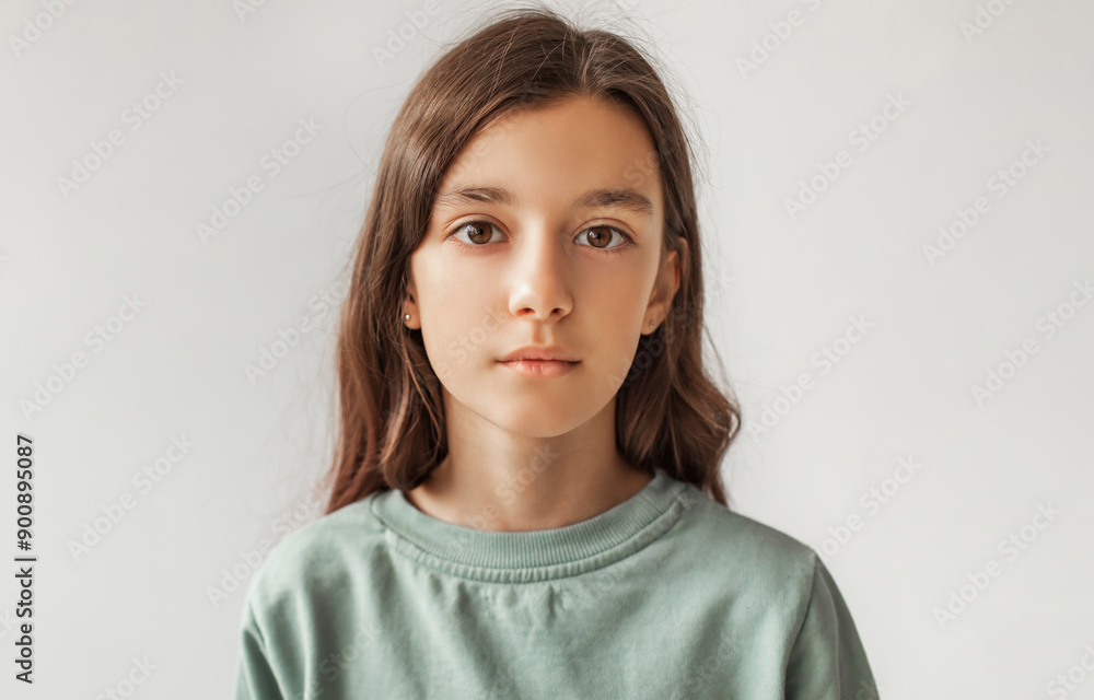 Portrait Of Serious Preteen Girl Standing Looking At Camera Over Gray Studio Background. Calm Kid Posing Wearing Casual Clothes, Headshot. Children Fashion Concept. Front View Portrait Of Serious Preteen Girl Standing Looking At Camera Over Gray Studio Background. Calm Kid Posing Wearing Casual Clothes, Headshot. Children Fashion Concept. Front View