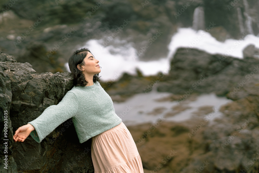 Young woman relaxing on a rocky beach in winter Young woman relaxing on a rocky beach in winter