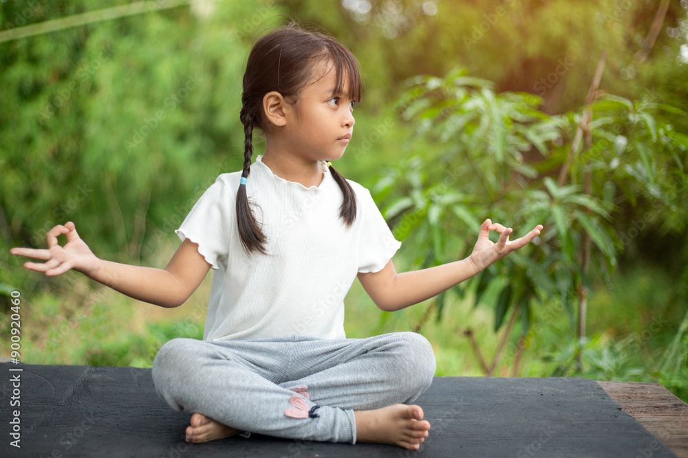 A little girl practices yoga in the backyard, surrounded by the refreshing embrace of nature. A little girl practices yoga in the backyard, surrounded by the refreshing embrace of nature.