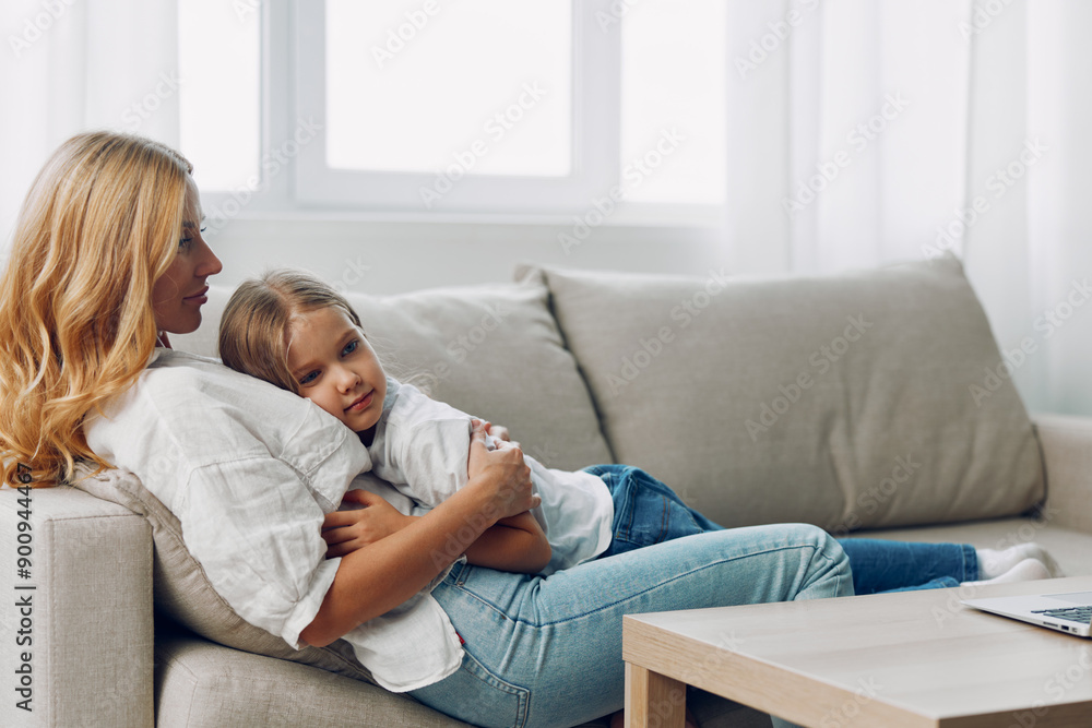Mother and child sharing a cozy moment on the couch, engaged with a laptop screen in a comfortable living room Mother and child sharing a cozy moment on the couch, engaged with a laptop screen in a comfortable living room
