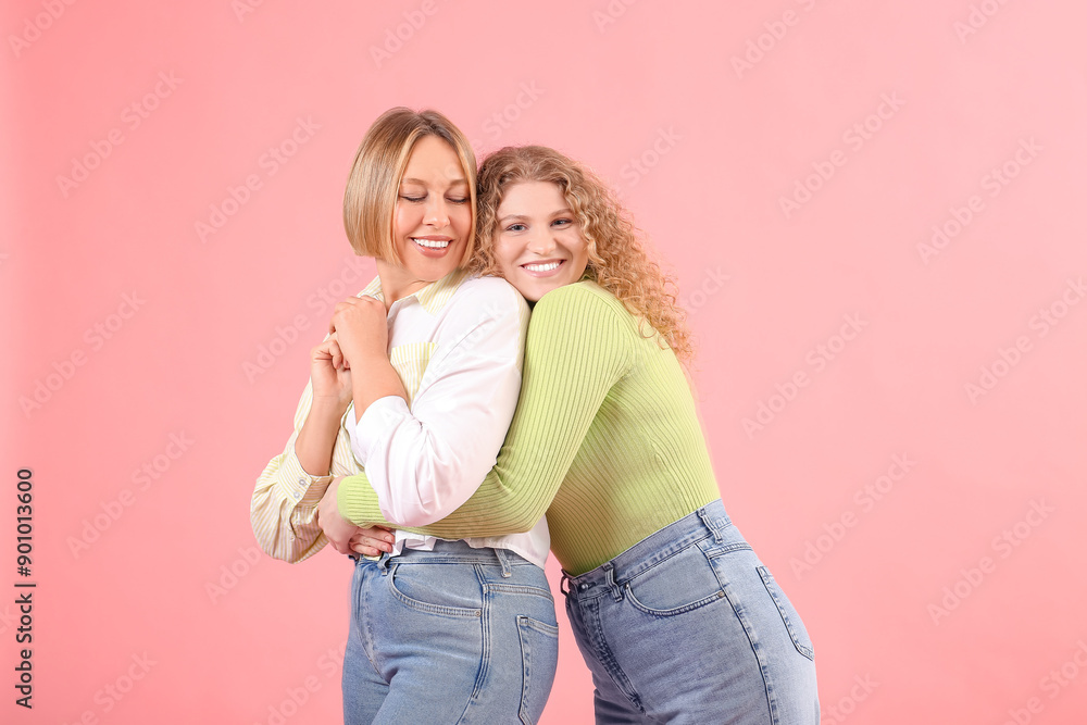 Beautiful happy women in stylish jeans hugging on pink background Beautiful happy women in stylish jeans hugging on pink background