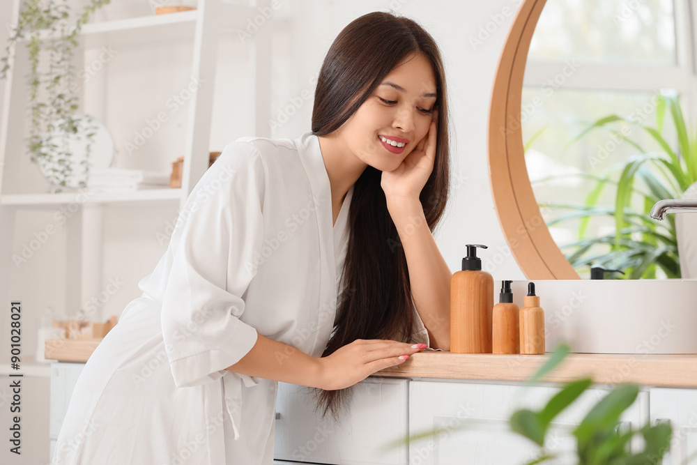 Young Asian woman with hair products in bathroom