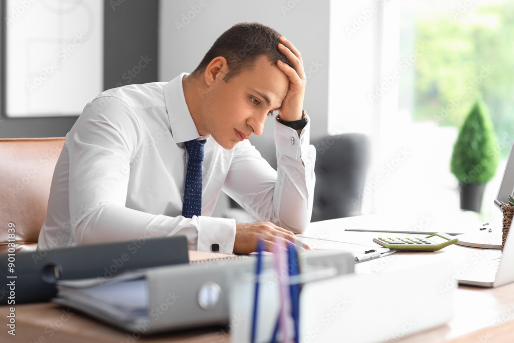 Tired male accountant working at desk in office Tired male accountant working at desk in office