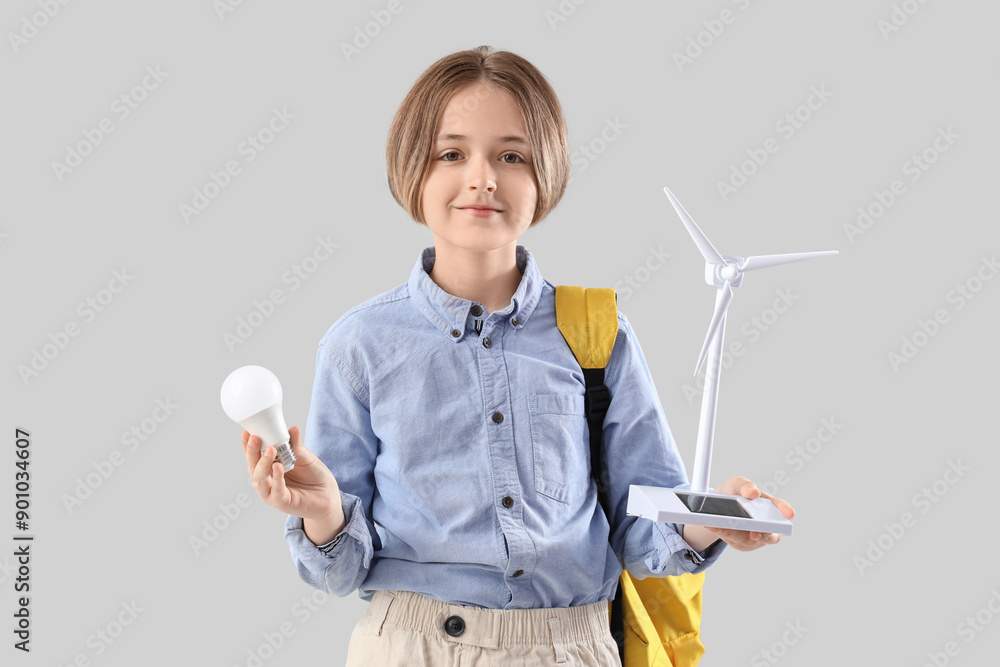 Teenage boy with wind turbine model and light bulb on light background. Ecology concept Teenage boy with wind turbine model and light bulb on light background. Ecology concept