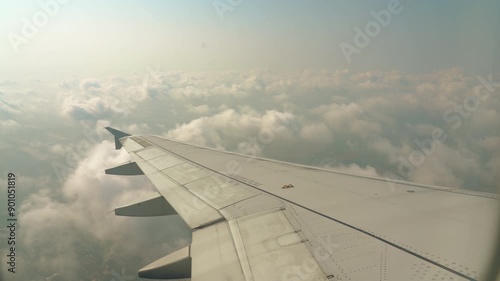 Window seat view of plane flying high above the clouds blue skies travel flight. Passenger view from airplane window flying above the sky. Travel concept