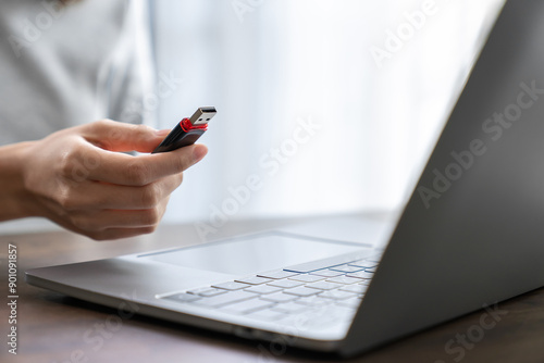 Hand holding usb flash drive with connecting to laptop at wooden table photo