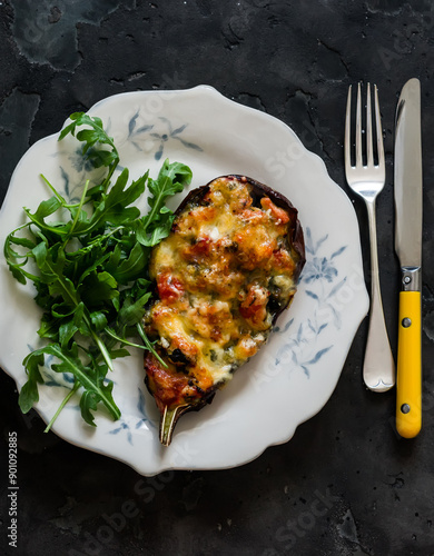 Stuffed with chicken, spinach, tomatoes and mozzarella cheese eggplant and arugula salad on a dark surface