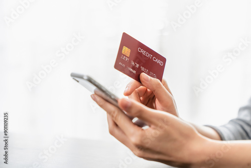 Woman hand holding a credit card and using smartphone to pay online. The concept of online shopping and payment.