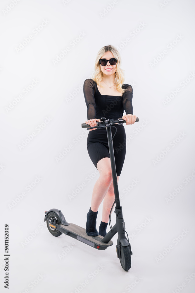 Fototapeta premium Woman ride e-scooter looking camera isolated on white background studio portrait. Lifestyle concept