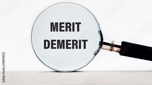 Merit, demerit and its retributions at the level of the individual. MERIT DEMERIT words through a magnifying glass on a light gray background photo