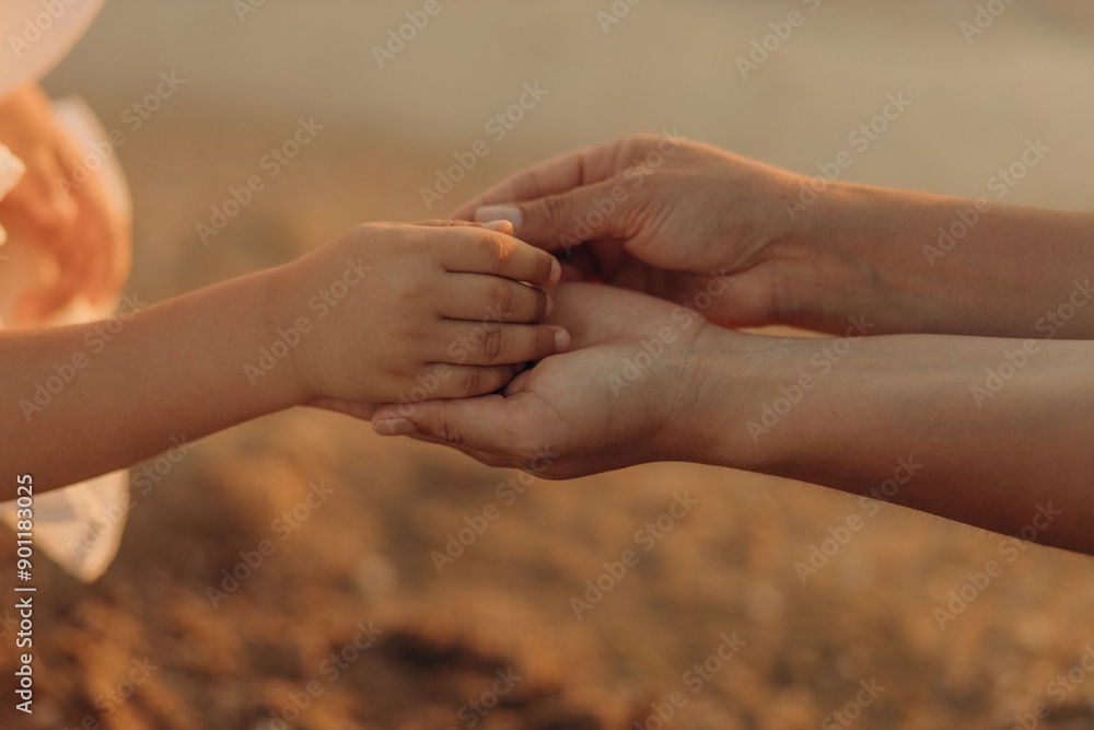 Close-up of two mother's hands holding a child's hand against the background of the sea. Close-up of two mother's hands holding a child's hand against the background of the sea.