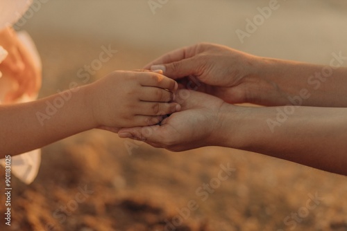 Close-up of two mother's hands holding a child's hand against the background of the sea.  