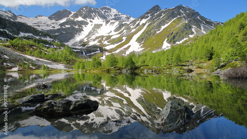 Reflections on The Lago Arpy (Arpy lake) located in the Italian Alps, La Thuile, Aosta Valley, surrounded by mountains and glaciers photo