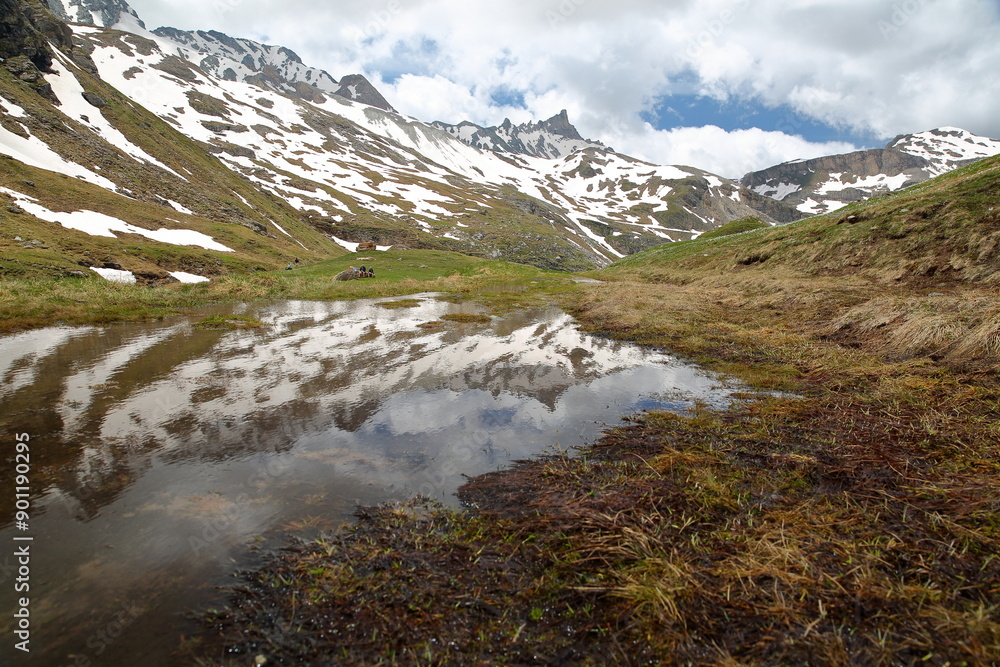 Reflection of mountain peaks from a hiking trail leading to Rhemes Golette glacier, at the bottom of Sassiere valley (Grande Sassiere natural reserve), Tignes, Northern French Alps, Savoie, France Reflection of mountain peaks from a hiking trail leading to Rhemes Golette glacier, at the bottom of Sassiere valley (Grande Sassiere natural reserve), Tignes, Northern French Alps, Savoie, France