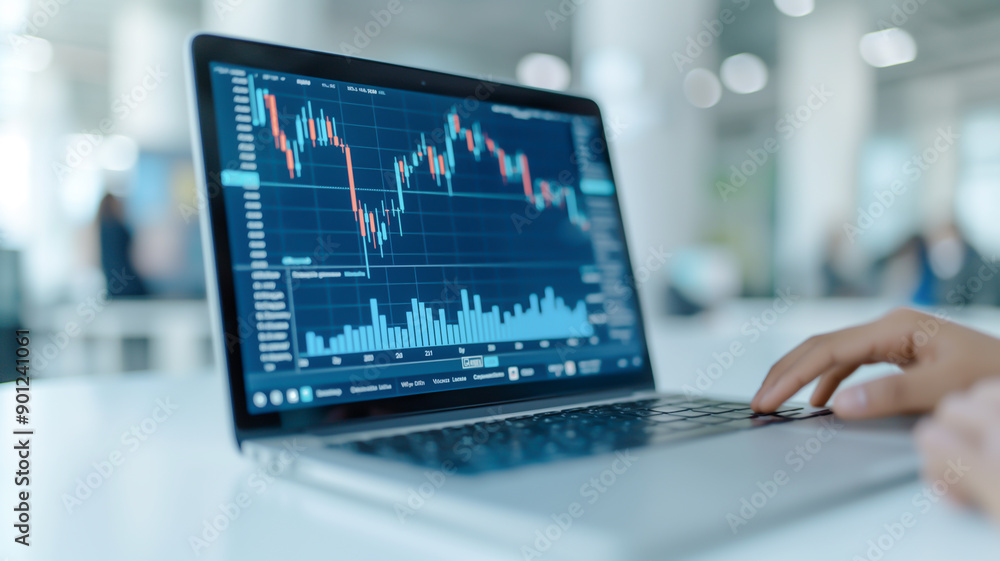 A close-up view of a laptop screen displaying stock market data, including candlestick charts and volume bars, in a modern office environment. A hand is poised over the keyboard, ready for analysis. A close-up view of a laptop screen displaying stock market data, including candlestick charts and volume bars, in a modern office environment. A hand is poised over the keyboard, ready for analysis.