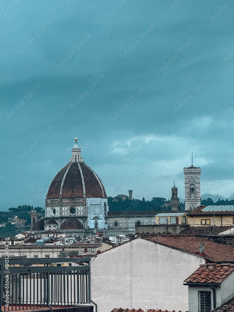 Fototapeta premium A large dome building with a clock tower in the background. The sky is cloudy and the buildings are white