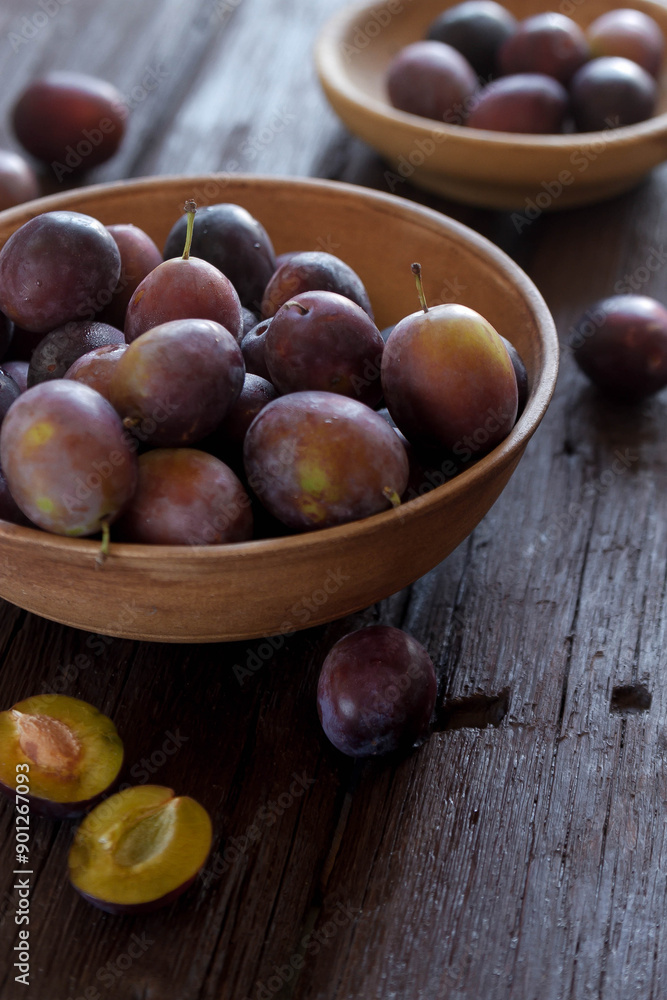 Fototapeta premium Fresh plums on plate over dark stone background