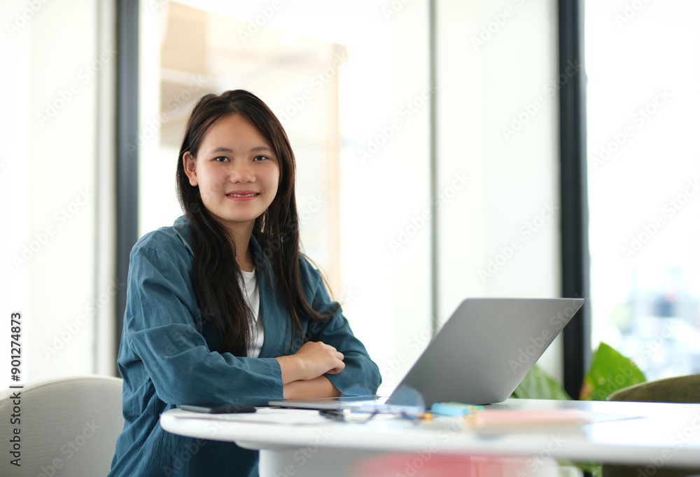 A woman is sitting at a desk with a laptop in front of her A woman is sitting at a desk with a laptop in front of her