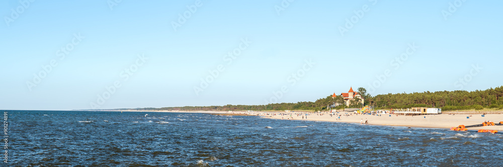 View of the beach in Leba. Beautiful wide beach on a sunny day. Castle and people in the distance. Leba, Poland