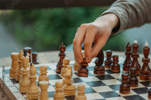 Hand of teenage boy placing chess piece on board photo