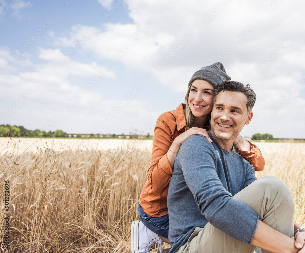 Contemplative couple sitting at field