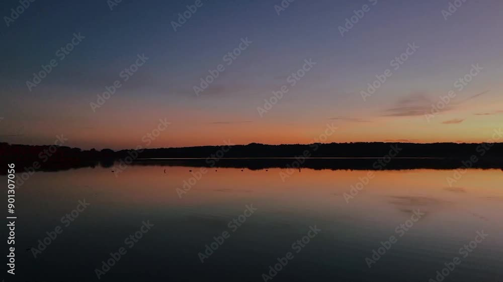 The bright sunset is reflected in the clear water of the lake The bright sunset is reflected in the clear water of the lake