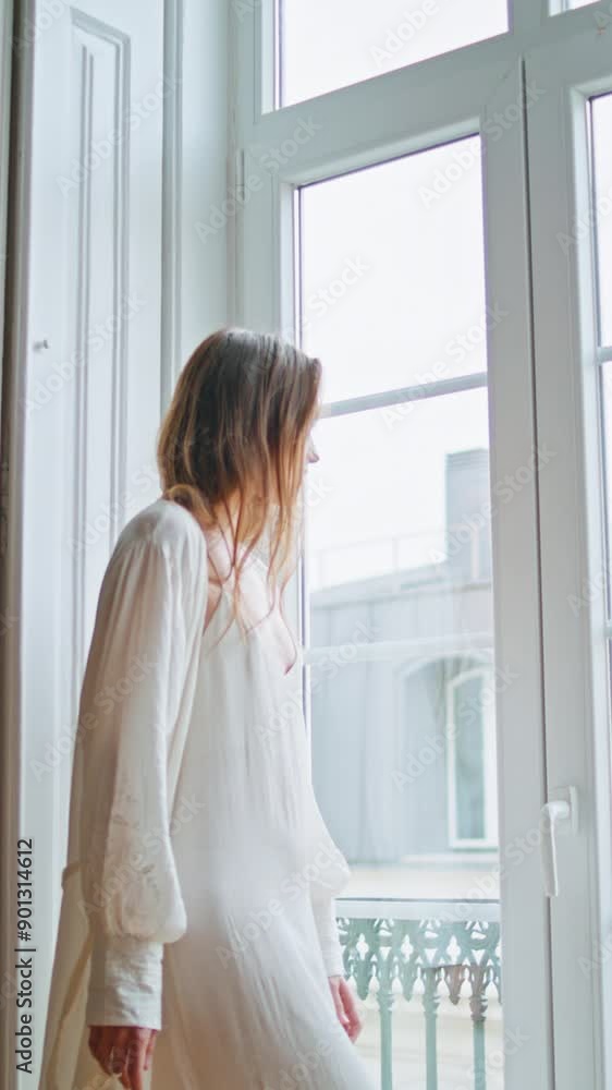 Young woman watching window home morning vertical closeup. Relaxed girl weekend