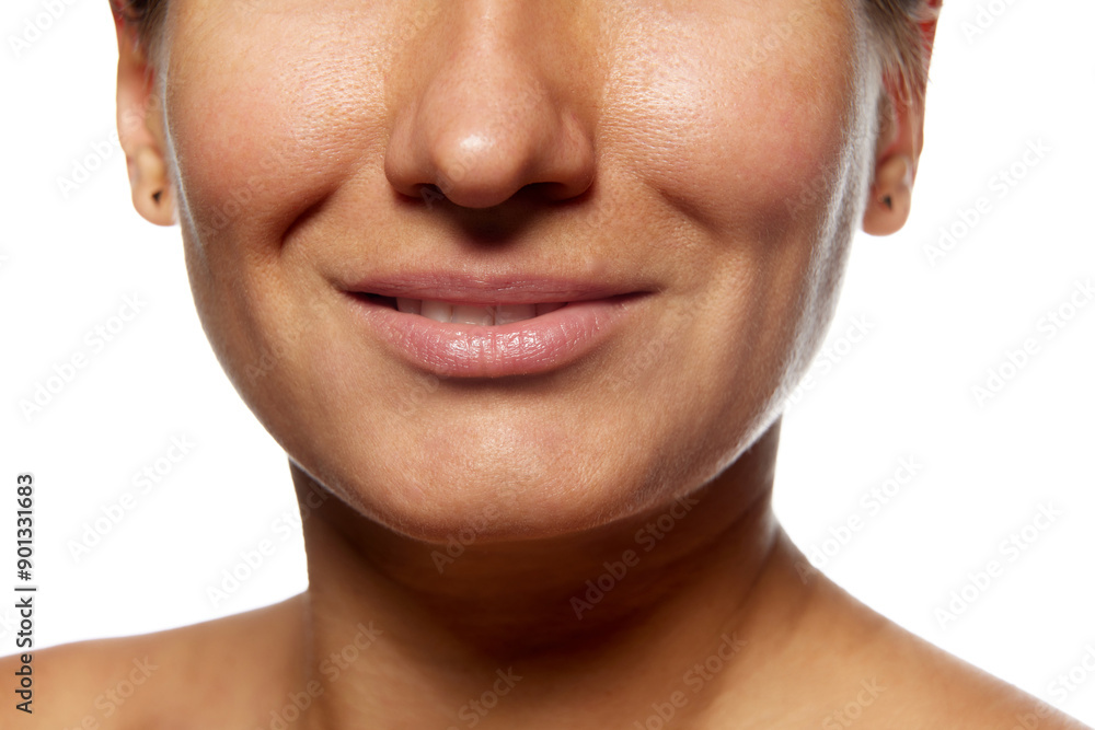 Obraz premium Cropped photo of woman's face with slight smile against white studio background. Face lifting and mimic wrinkles. Concept of facial care, lifting, spa procedures, anti-aging, surgery.