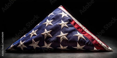 Isolated American national flag folded in triangular shape with creases, set against a pure black background, commemorating Memorial Day, with ample copy space for text overlay. photo