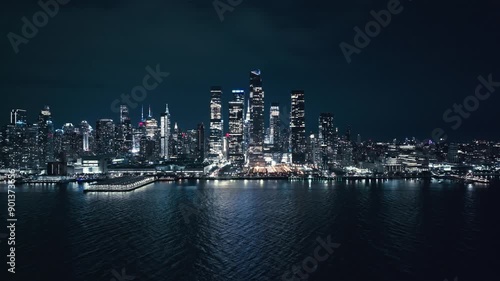 Aerial pullback over river with New York City skyline buildings sparkling at night photo