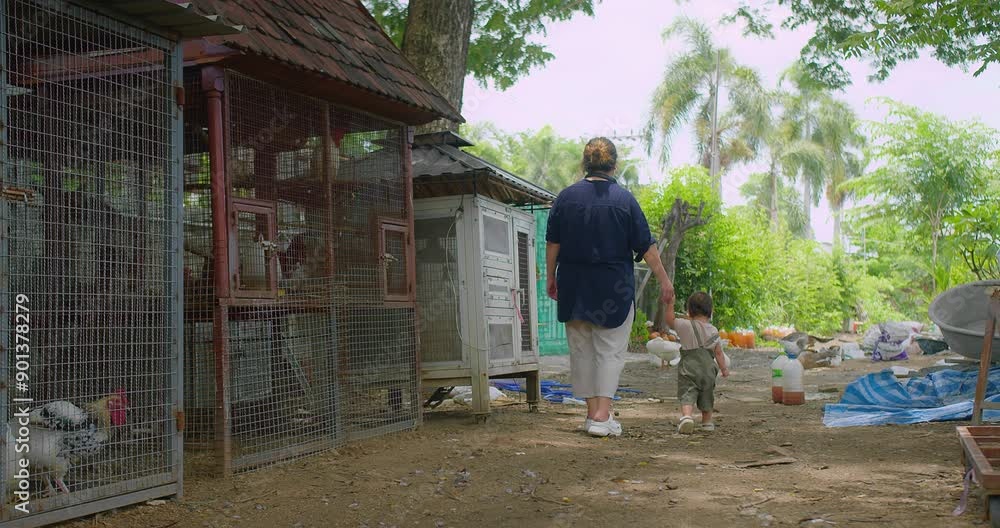Asian Mother and Child Walking Through a Rural Farm with Chicken Coops and Lush Greenery on a sunny day. Asian Mother and Child Walking Through a Rural Farm with Chicken Coops and Lush Greenery on a sunny day.