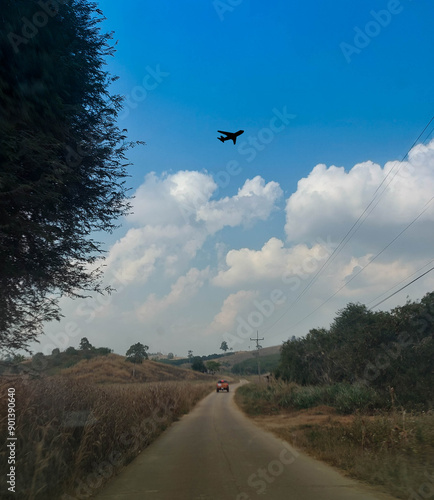 landscape Road in the countryside of nan Thailand with airplane flying in blue sky and white clouds. natural background texture.