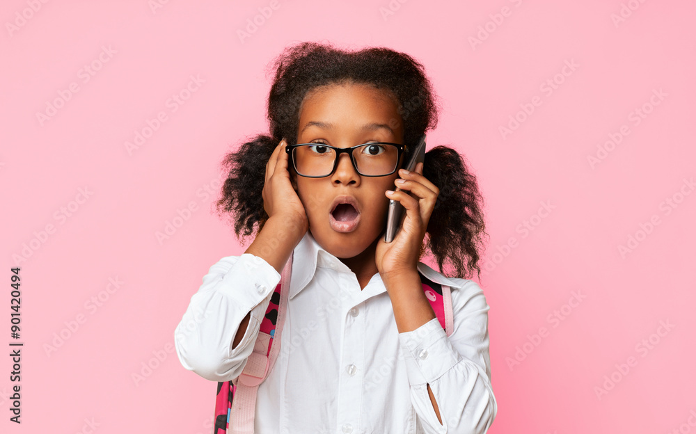 Oops. Shocked Black School Girl Talking On Phone Listening To Rumors With Opened Mouth Over Yellow Background. Studio Shot Oops. Shocked Black School Girl Talking On Phone Listening To Rumors With Opened Mouth Over Yellow Background. Studio Shot