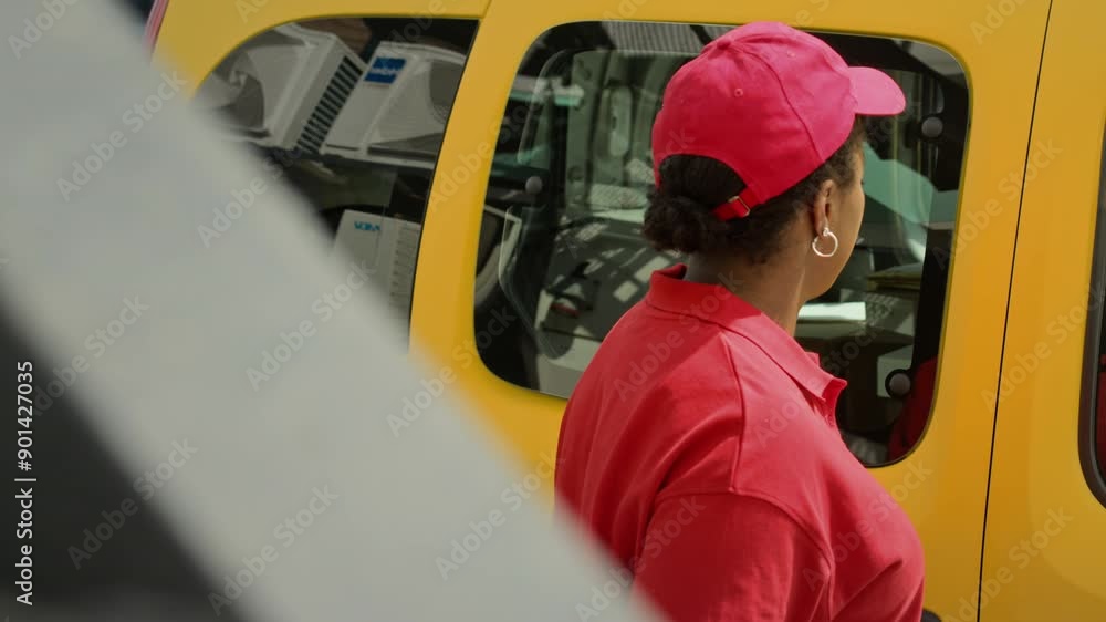Handheld shot of African American female agent delivering parcels to clients by yellow van Handheld shot of African American female agent delivering parcels to clients by yellow van