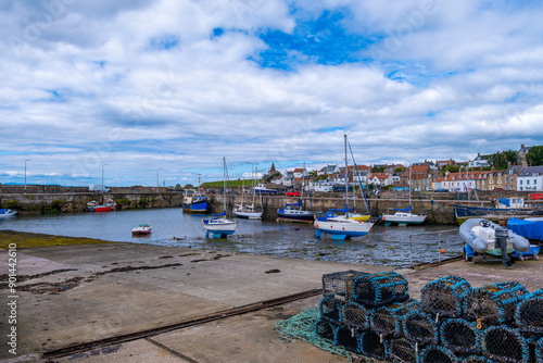 St Monans Harbour on the east coast of Scotland on the Fyfe coast  looking over lobster pots to the boats and the sea defences with the ancient church of the same name in the far distance. photo