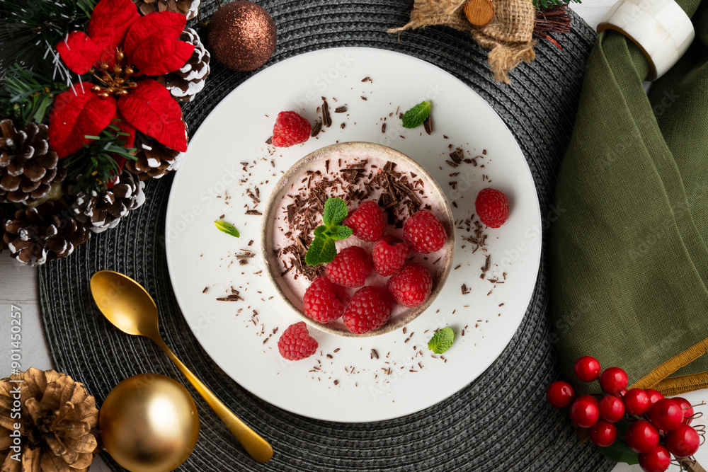 Delicious raspberry mousse with red berries from an overhead perspective. Table with Christmas decoration. Delicious raspberry mousse with red berries from an overhead perspective. Table with Christmas decoration.