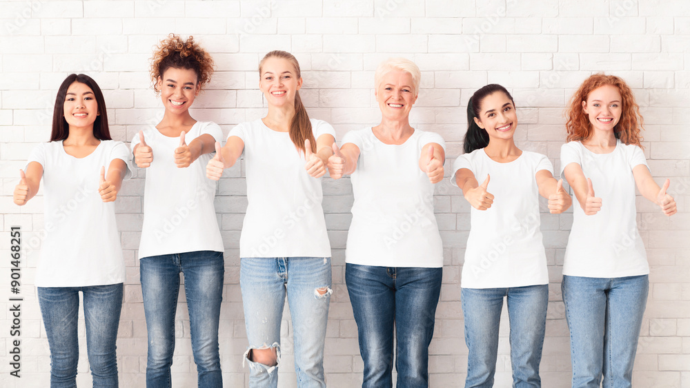 Fototapeta premium Breast Cancer. Group Of Mixed Ladies In Pink T-Shirts With Cancer Ribbons Gesturing Thumbs Up Standing On White Background. Panorama