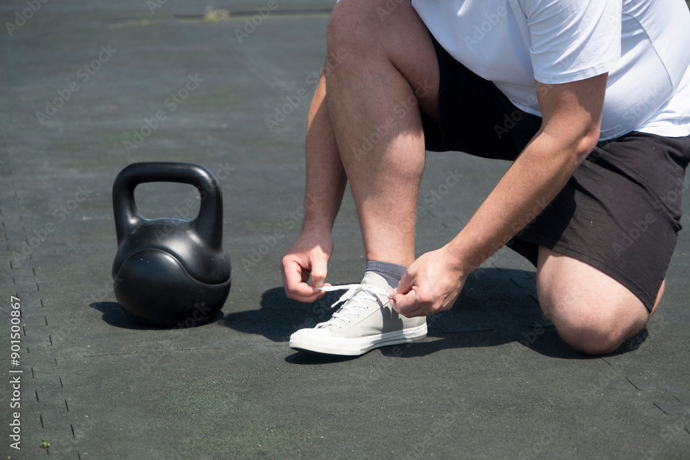 Naklejka premium Sportive man workout with kettlebell outdoor in spring or summer