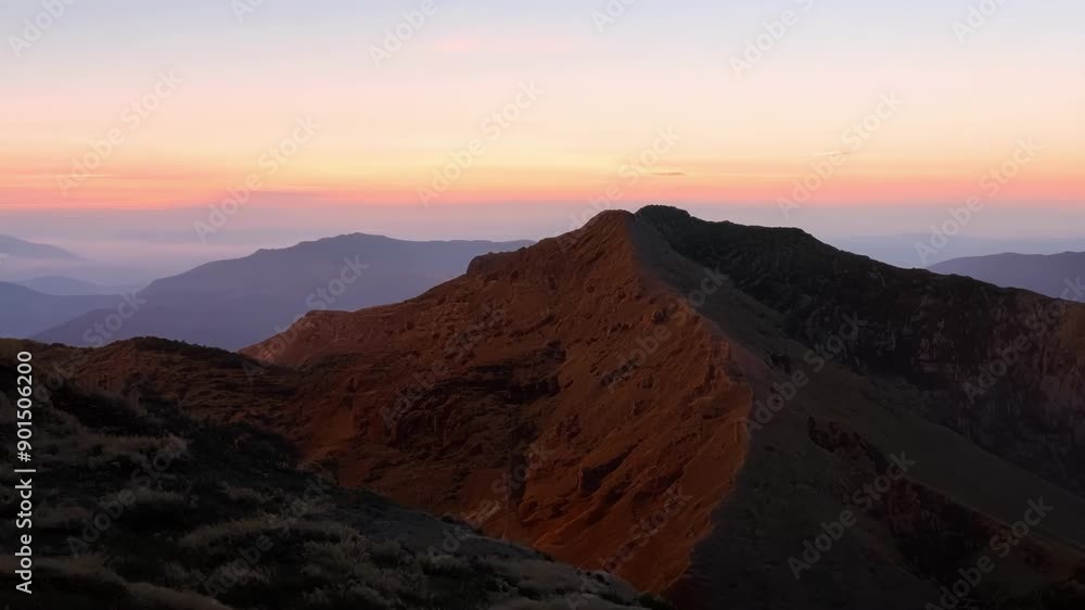 As the sky slowly changes from dark blue to shades of soft pink and orange the mountainside is bathed in a warm golden light. As the sky slowly changes from dark blue to shades of soft pink and orange the mountainside is bathed in a warm golden light.