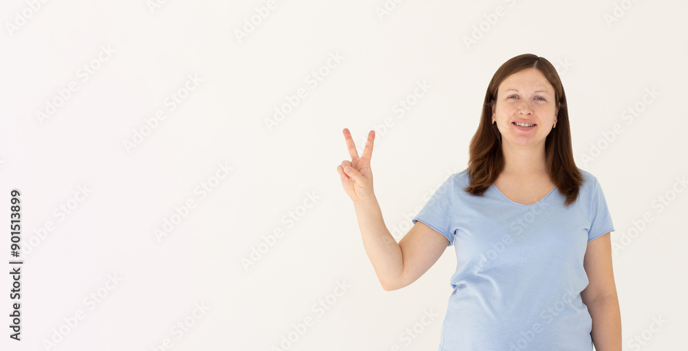 Young caucasian smiling happy friendly woman in stylish casual blue t-shirt show victory v-sign gesture isolated on white background studio portrait People lifestyle concept Young caucasian smiling happy friendly woman in stylish casual blue t-shirt show victory v-sign gesture isolated on white background studio portrait People lifestyle concept