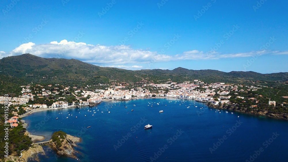 Fototapeta premium aerial view over the Badia de Cadaqués, to the old white houses of Cadaqués, Port Alguer and the turquoise water of the Mediterranean Sea, mountains of the Pyrenees behind, Girona, Catalonia, Spain