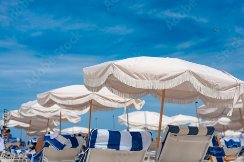 Beige parasol and striped chairs by the beachfront at Miami Beach. photo