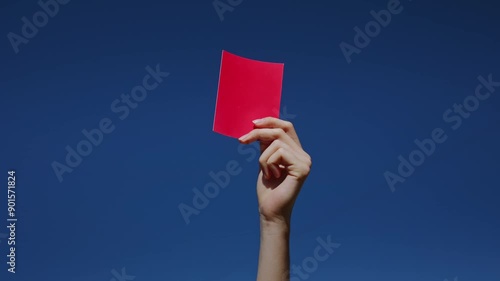 The hand holds a red card. Violation of the rules.