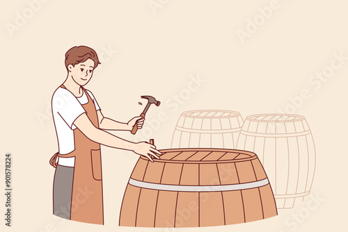 Man winemaker opens barrel with finished drink to taste bordeaux made from organic grapes. Guy is standing in wine cellar, hammering barrel of sherdane to infuse and impart unique smell to wine.