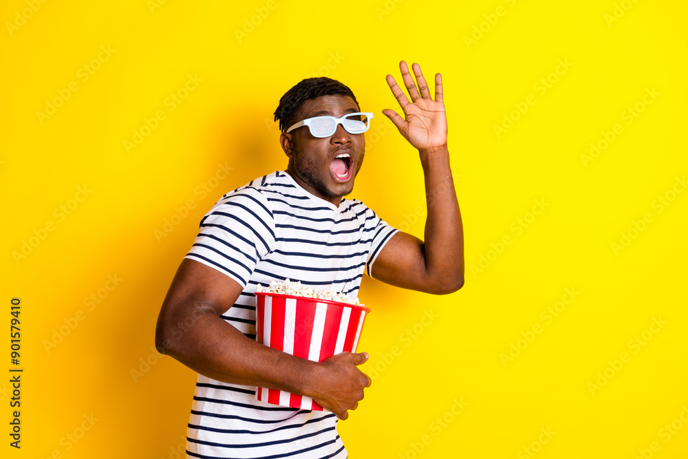 Photo of nice young man 3d glasses popcorn cinema wear striped t-shirt isolated on bright yellow color background Photo of nice young man 3d glasses popcorn cinema wear striped t-shirt isolated on bright yellow color background