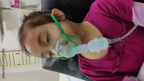 An Asian kid using nebulizer masks by themselves smokes, breathes in steam, coughs, uses an oxygen spray inhaler, and has a stuffy or runny nose. 4K Vertical